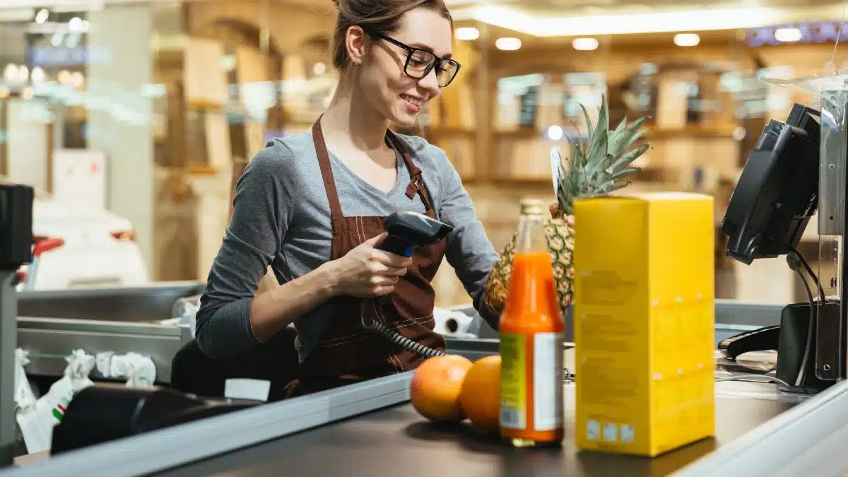Smiling female cashier scanning grocery items