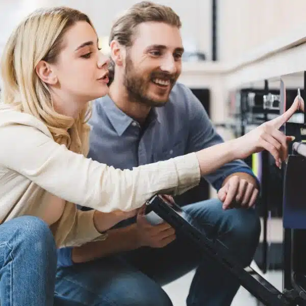 Woman using oven and smiling consultant looking at it in home appliance