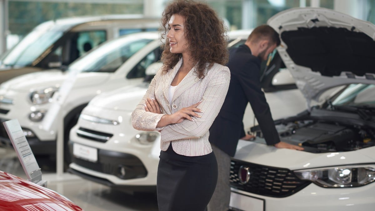 Key Checks That Make Cars Affordable Woman walking in car store, manager working on background