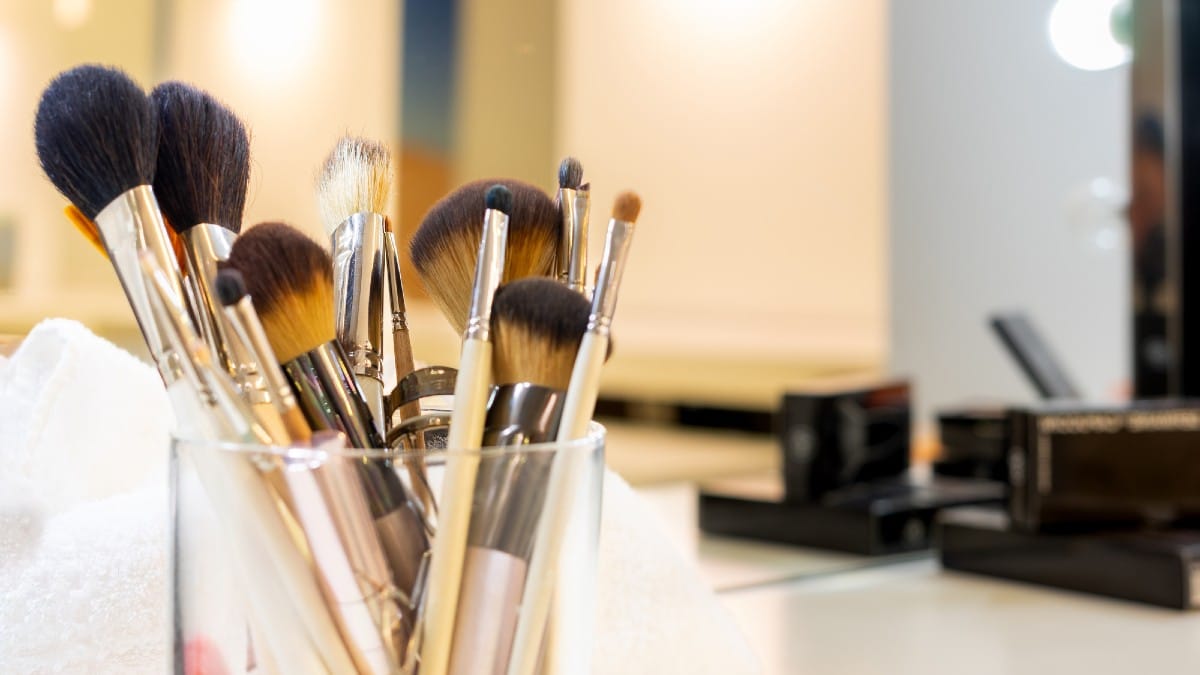15 Used Bargains That Can Secretly Cost You More Several make-up brushes inside glass container on work table in a hairdr