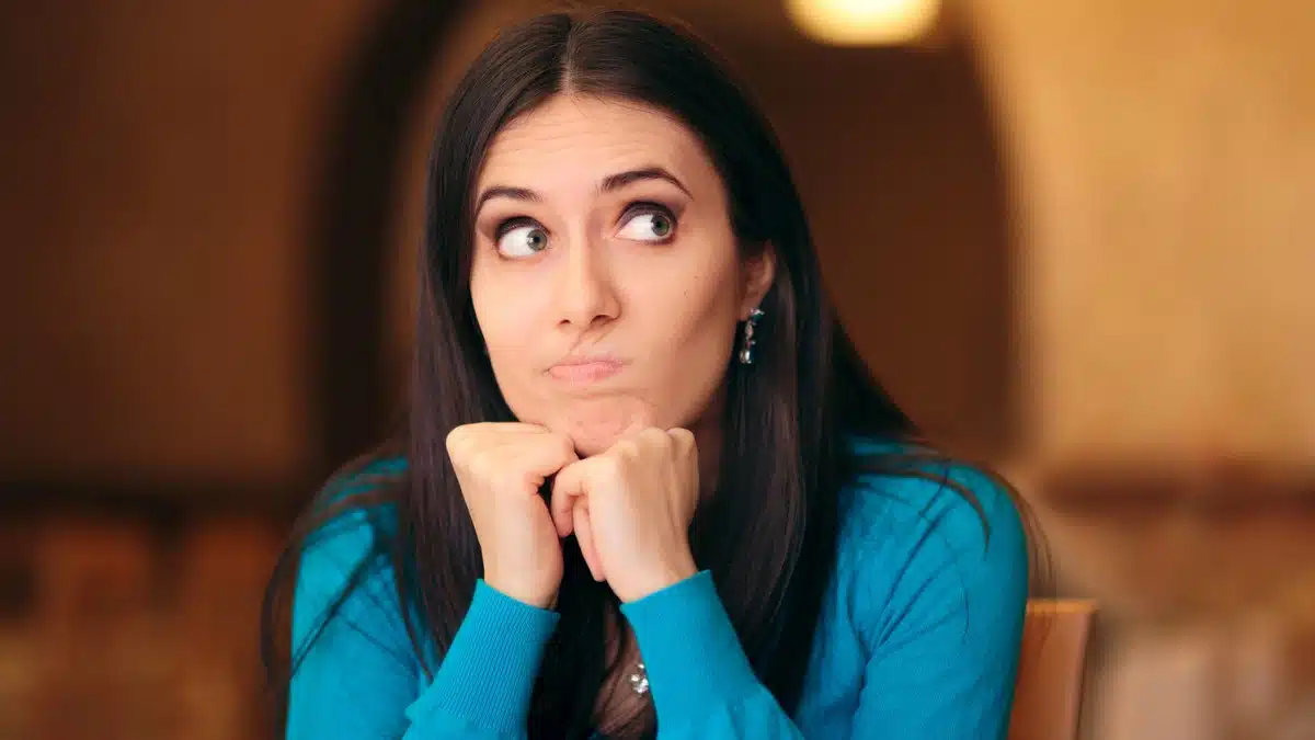 6 Simple Ways To Stop Spending So Much Money woman thinking with hands on chin