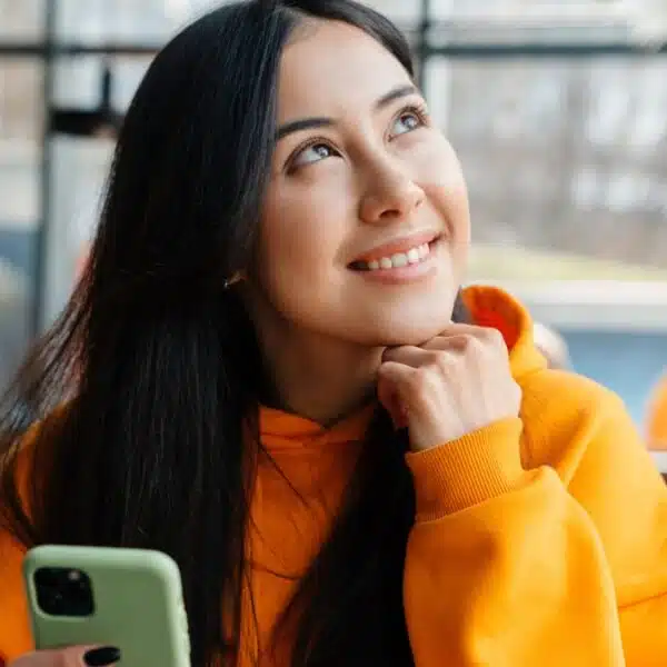 woman in hoodie holding her phone