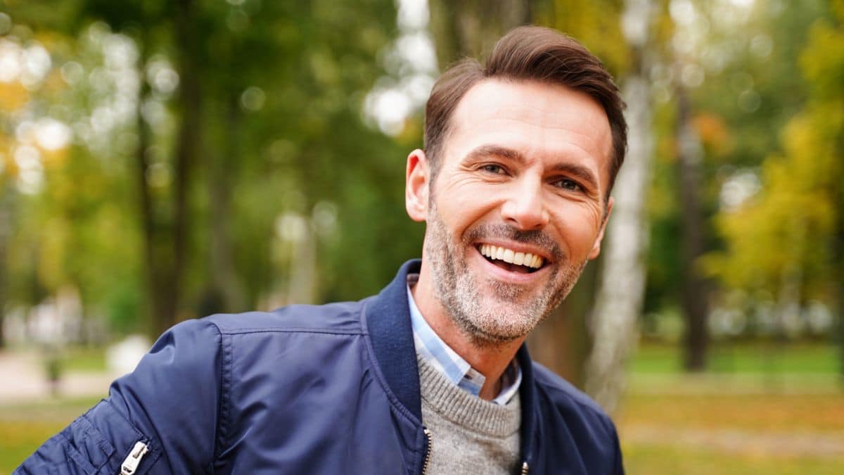 Signs Someone Is Wealthy Without Showing It man smiling in fall time