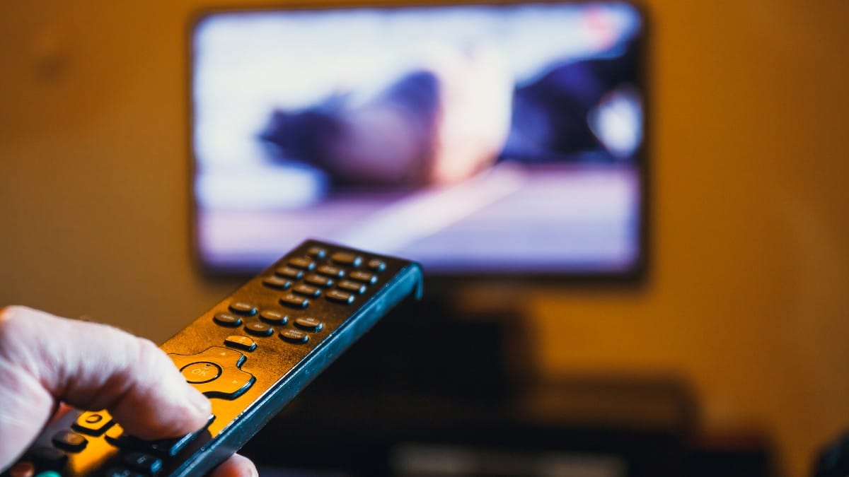 20 Things Minimalists Refuse to Spend Money On Hand-holding-TV-remote-control-and-presses-the-button