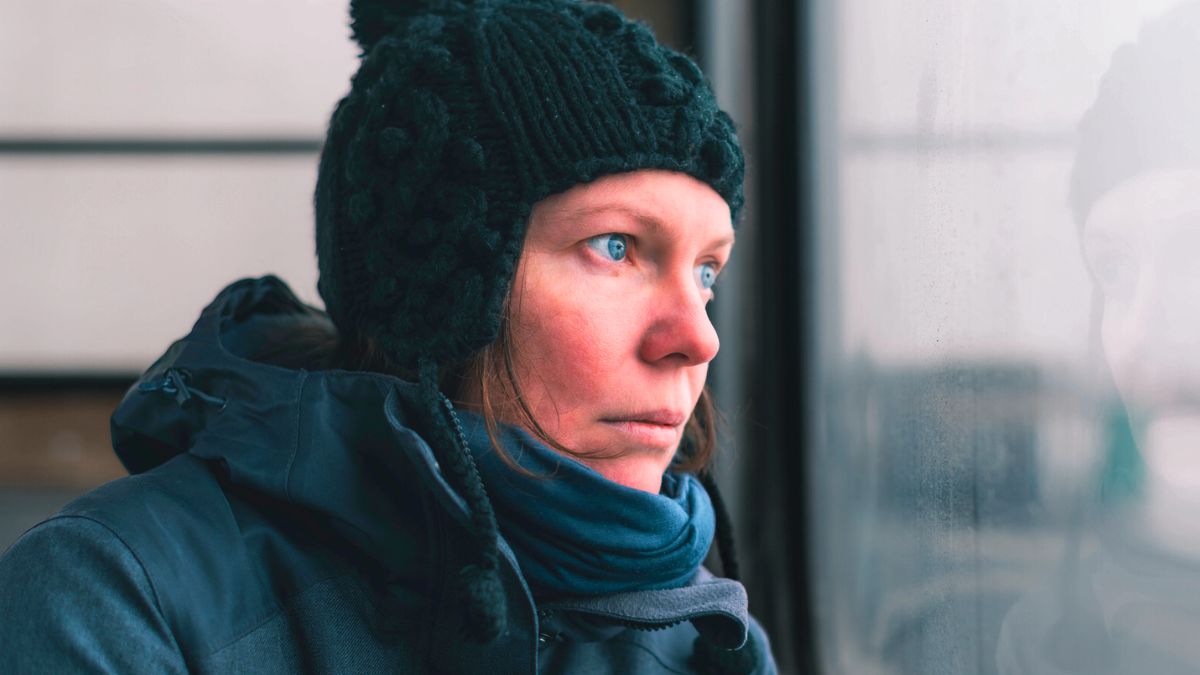 woman cold looking out the window sad