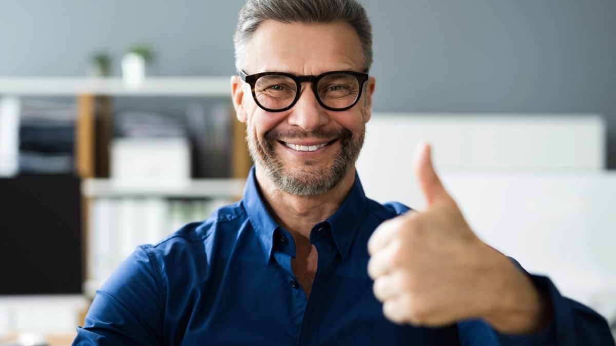 15 Mindset Shifts That Make You Richer man glasses smiling thumbs up office