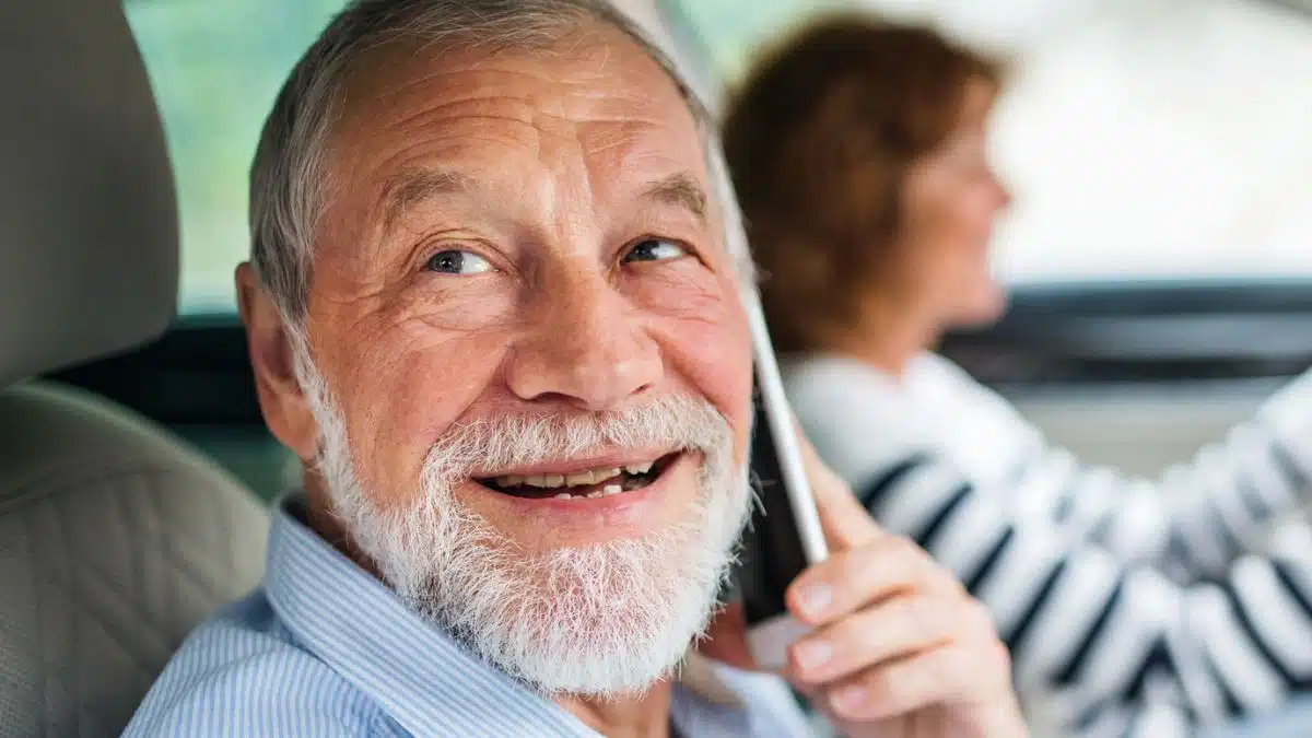 elder man in car with phone
