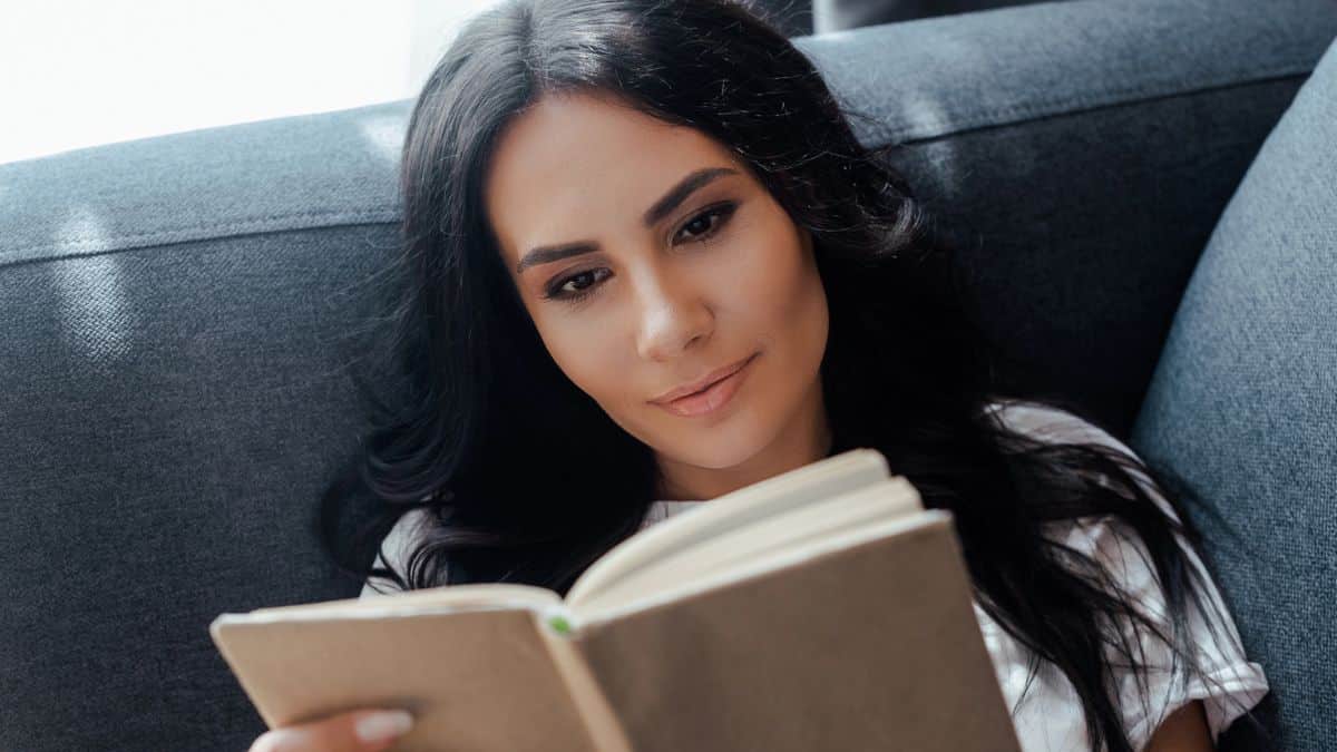 laying on a couch reading a book