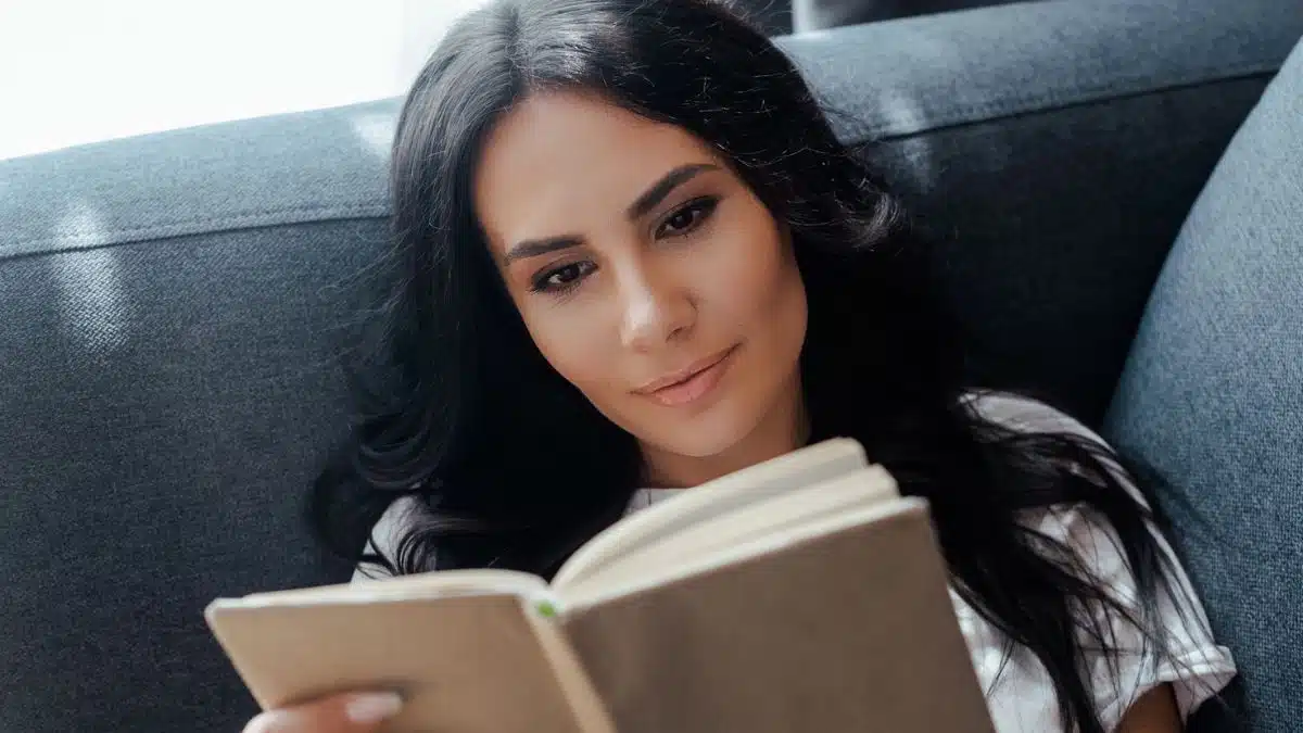 laying on a couch reading a book