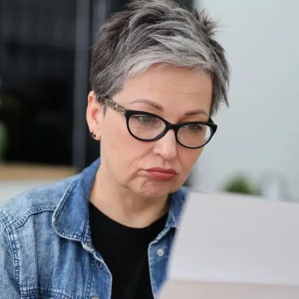 mature woman glasses reading mail sad