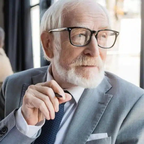 senior man glasses looking at the window suuit and tie