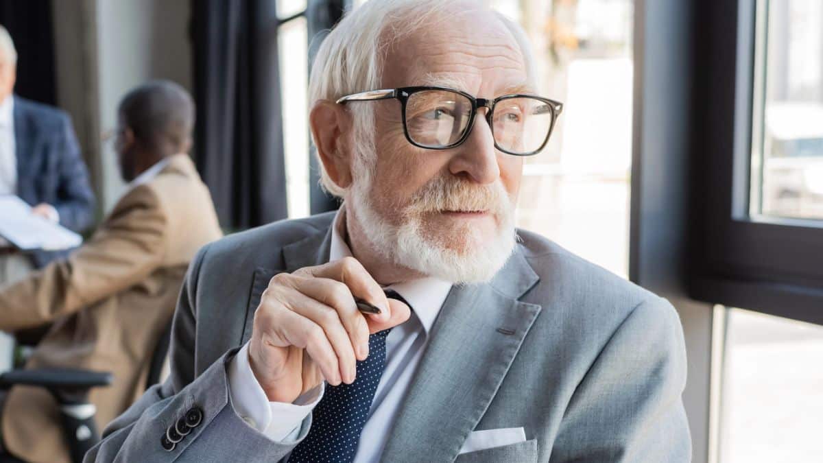 senior man glasses looking at the window suuit and tie