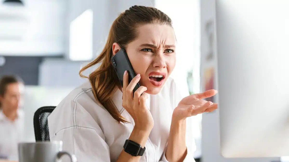 woman desk phone computer unhappy angry