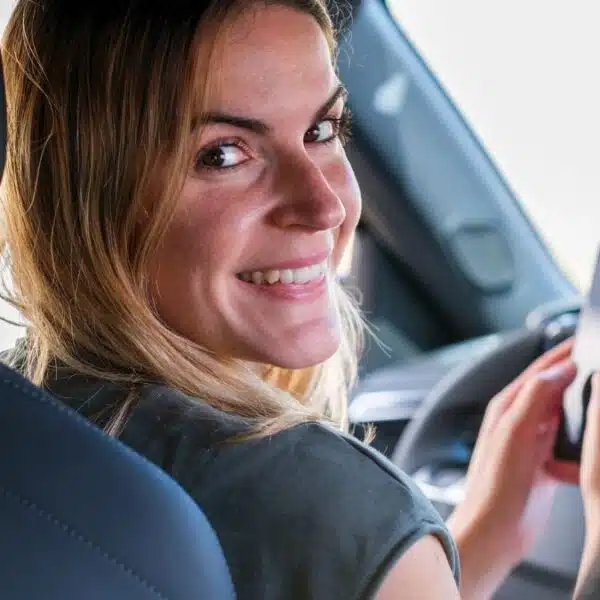 woman in car on phone texting smiling backwards