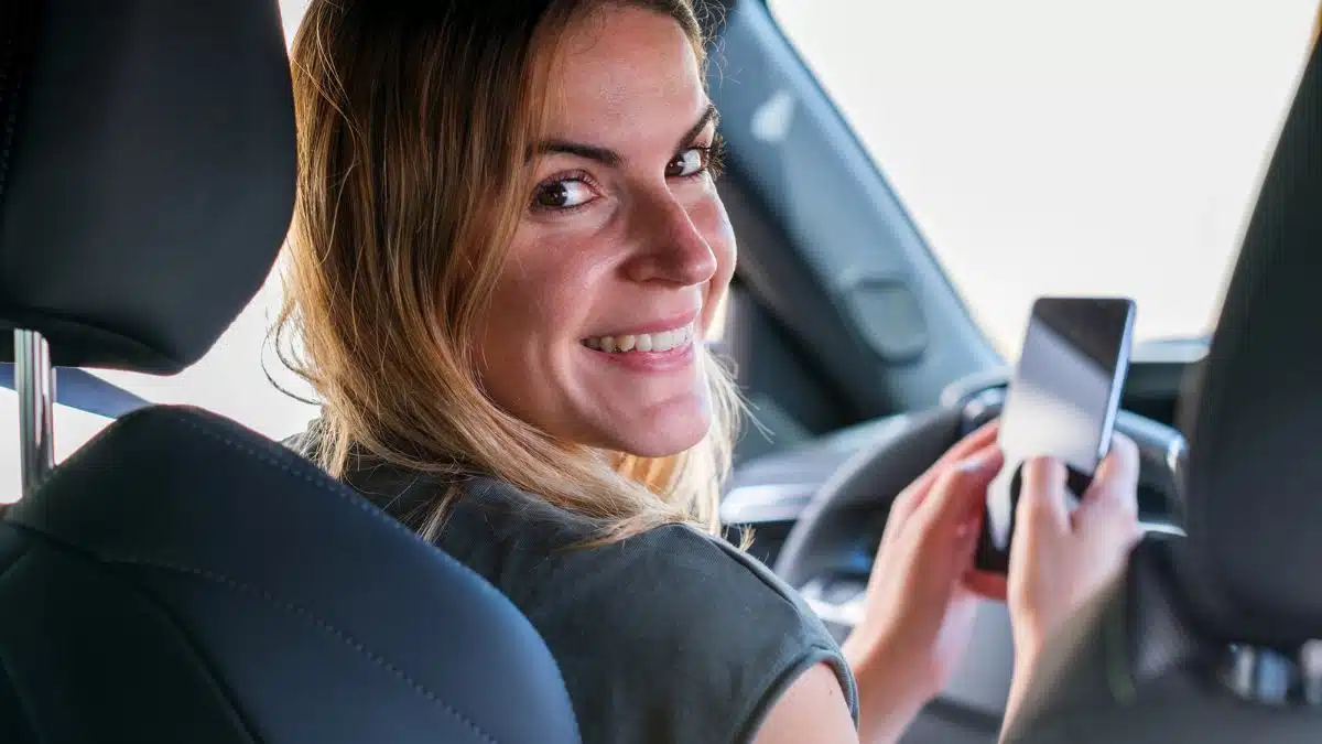 woman in car on phone texting smiling backwards