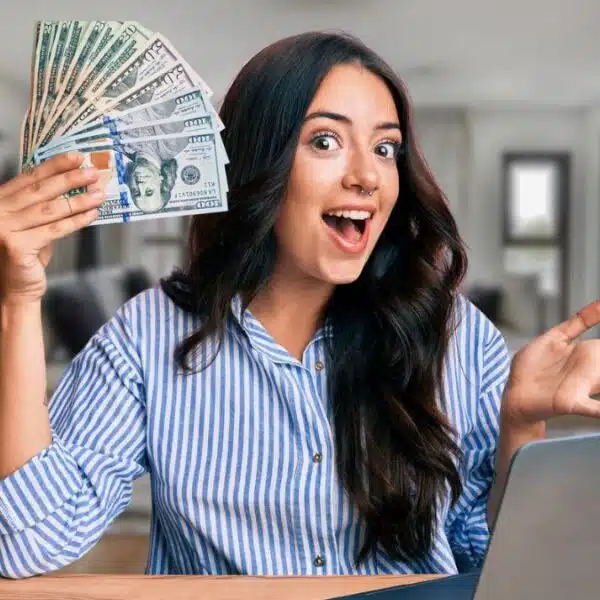 woman holding cash at a computer