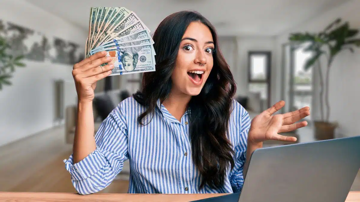 woman holding cash at a computer