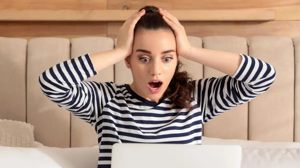 woman shocked in bed with laptop