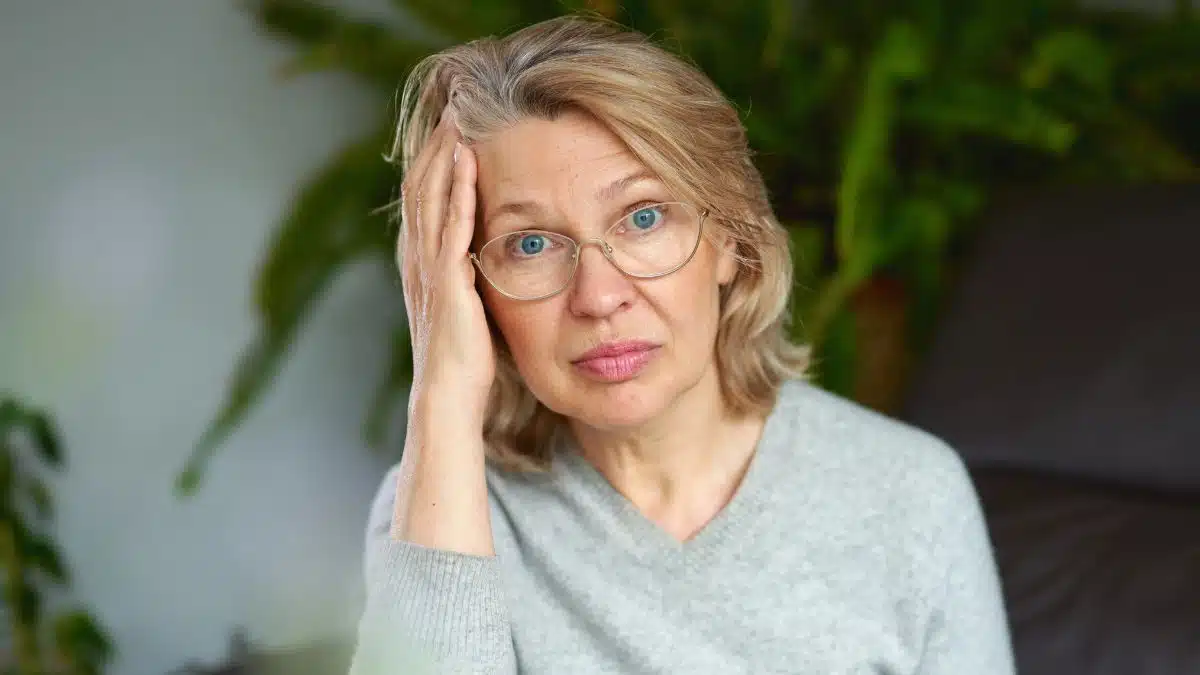 mature woman confused with glasses on couch