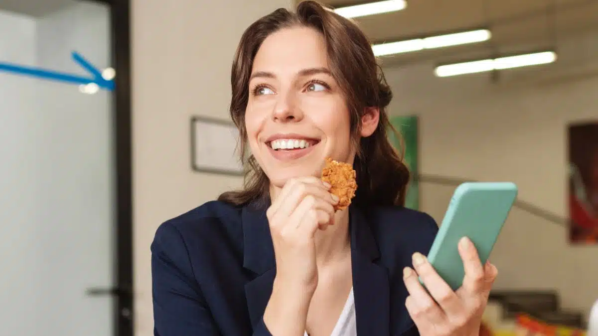 woman eating at her desk phone
