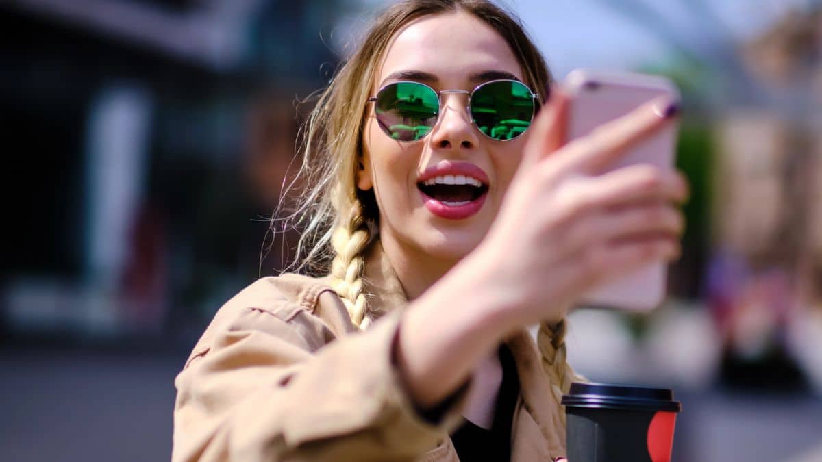 woman sunglasses walking outside holding phone