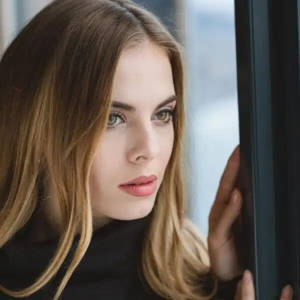 blonde woman looking out the window