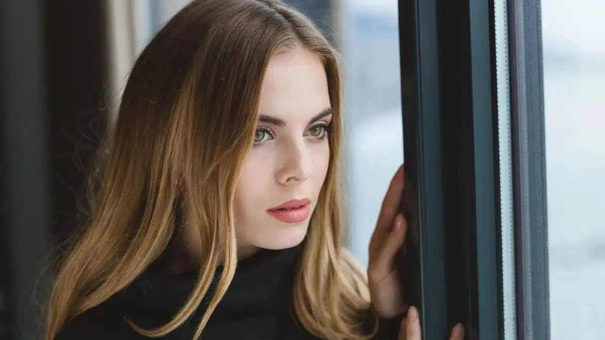 blonde woman looking out the window