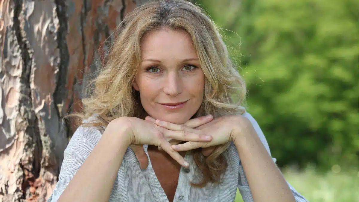 mature woman leaning on a tree