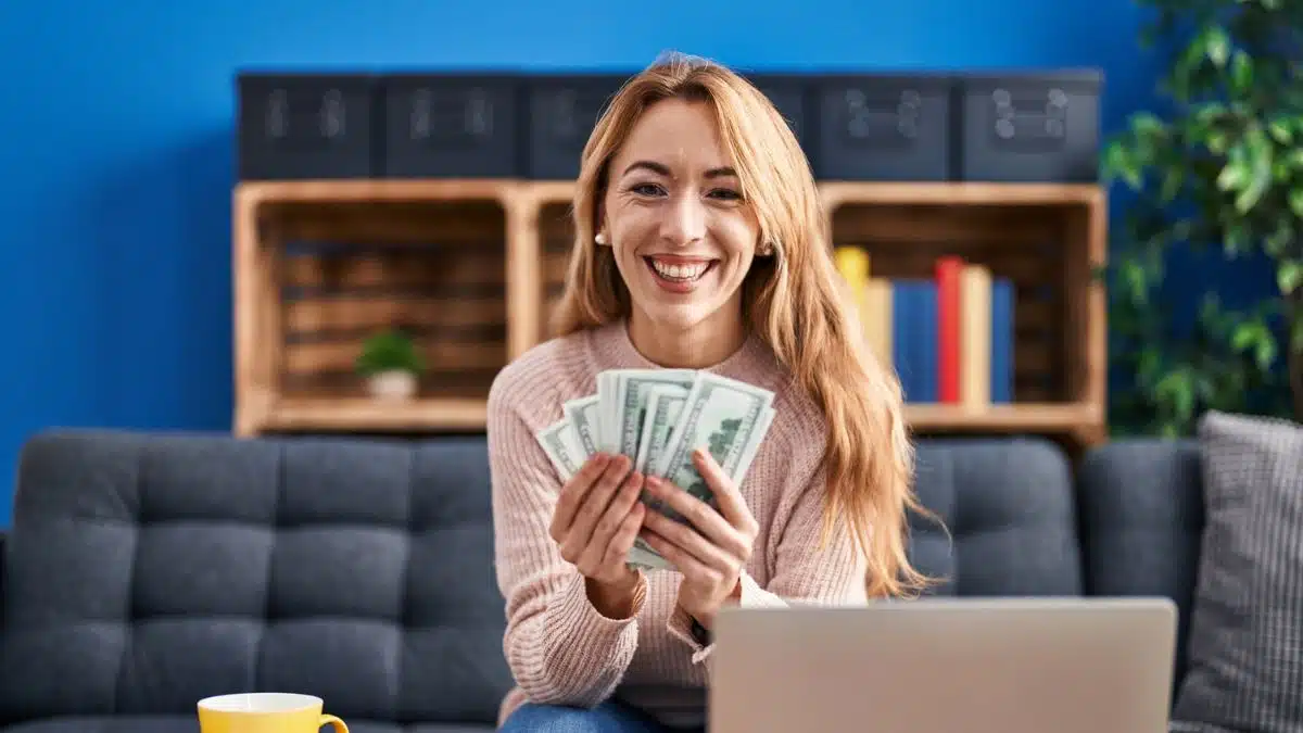 woman holding cash sitting on the couch
