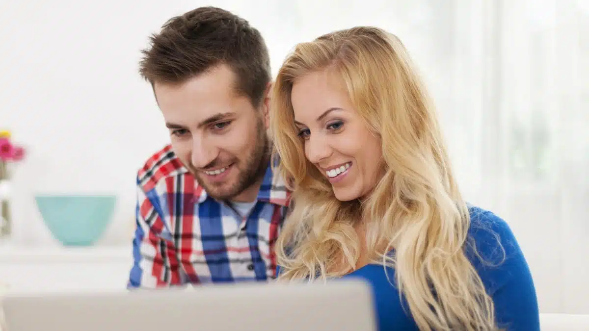 Happy couple sharing thoughts on their laptop