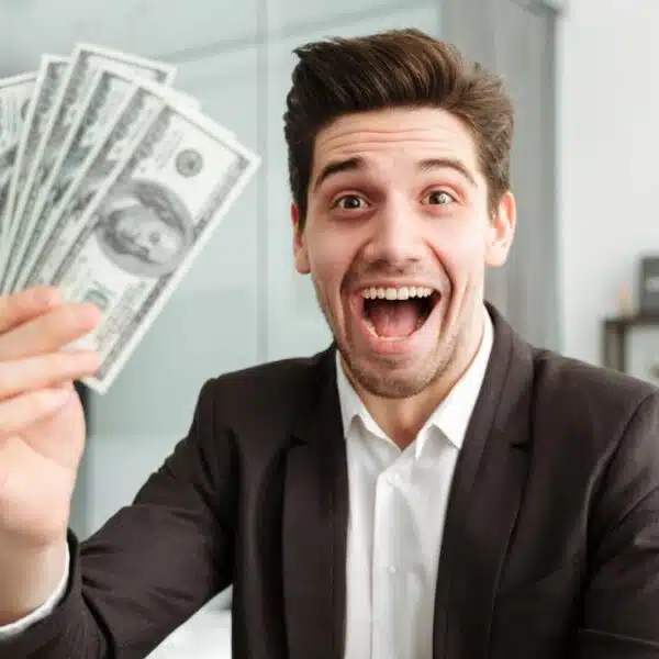 man holding cash in front of a laptop