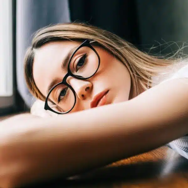 woman resting her head down with glasses