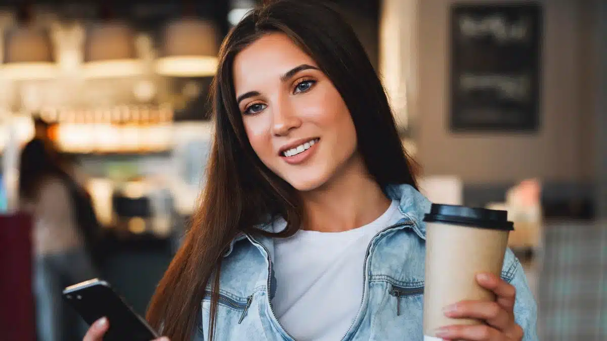 woman sitting in a coffee shop holding her phone