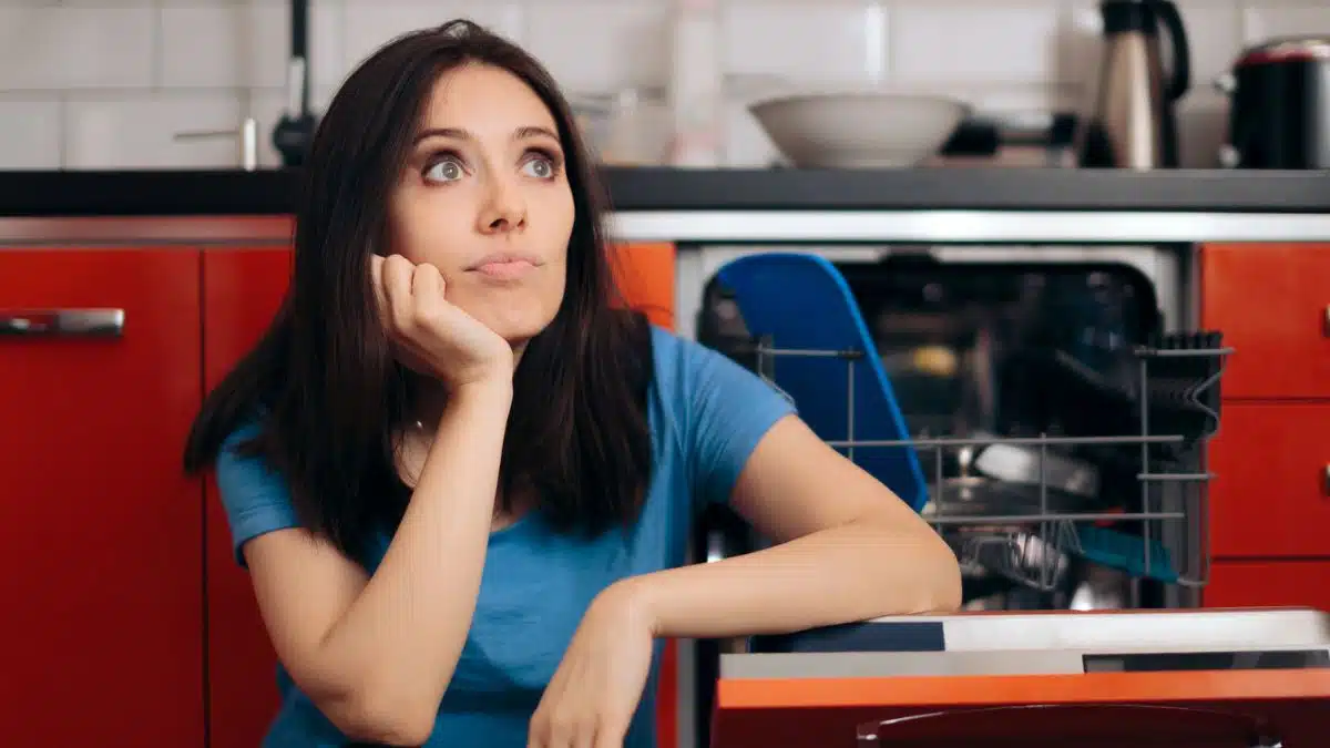 woman sitting next to a dishwasher