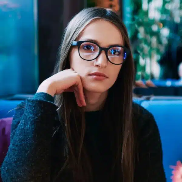 woman wearing glasses sitting in a booth
