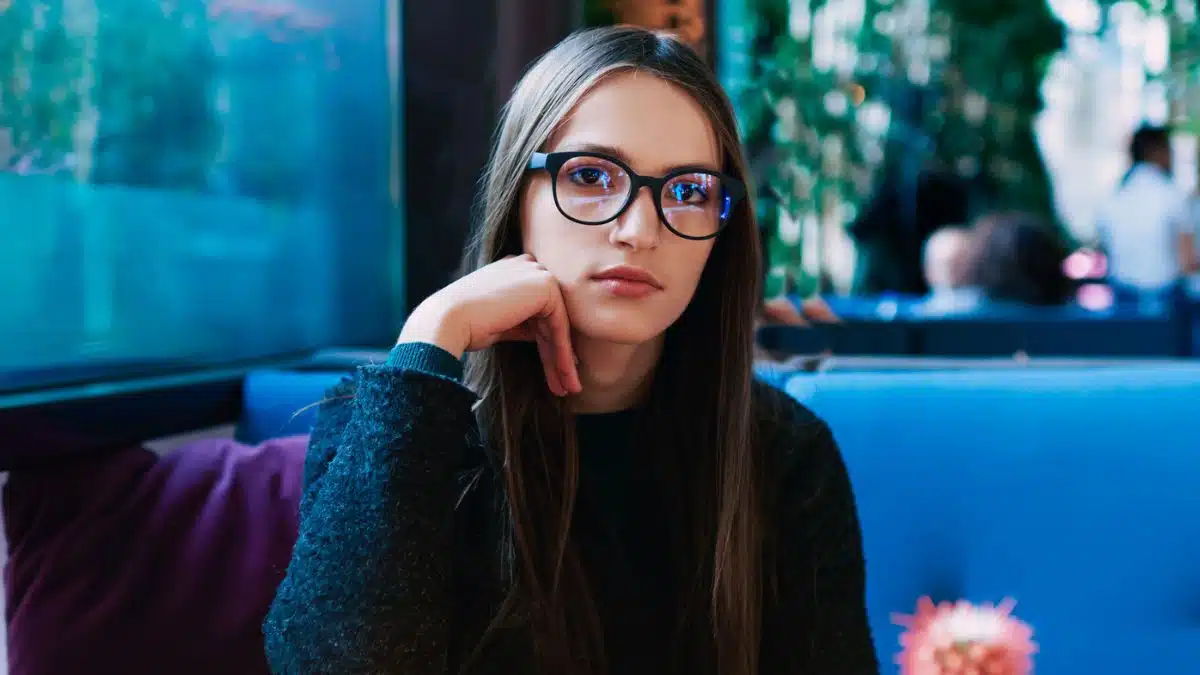 woman wearing glasses sitting in a booth
