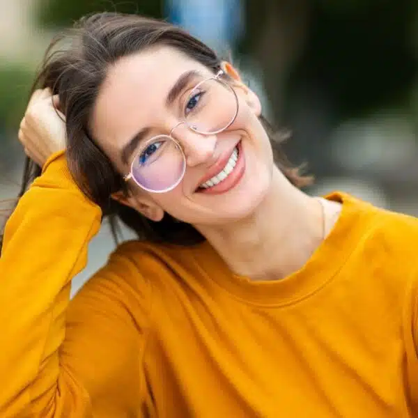 woman with glasses smiling alone in park