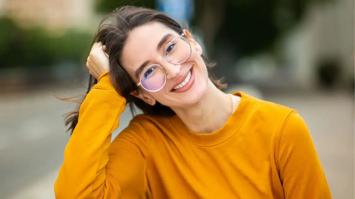 woman with glasses smiling alone in park