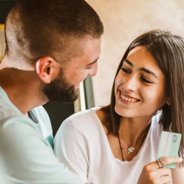 couple smiling at one another with credit card