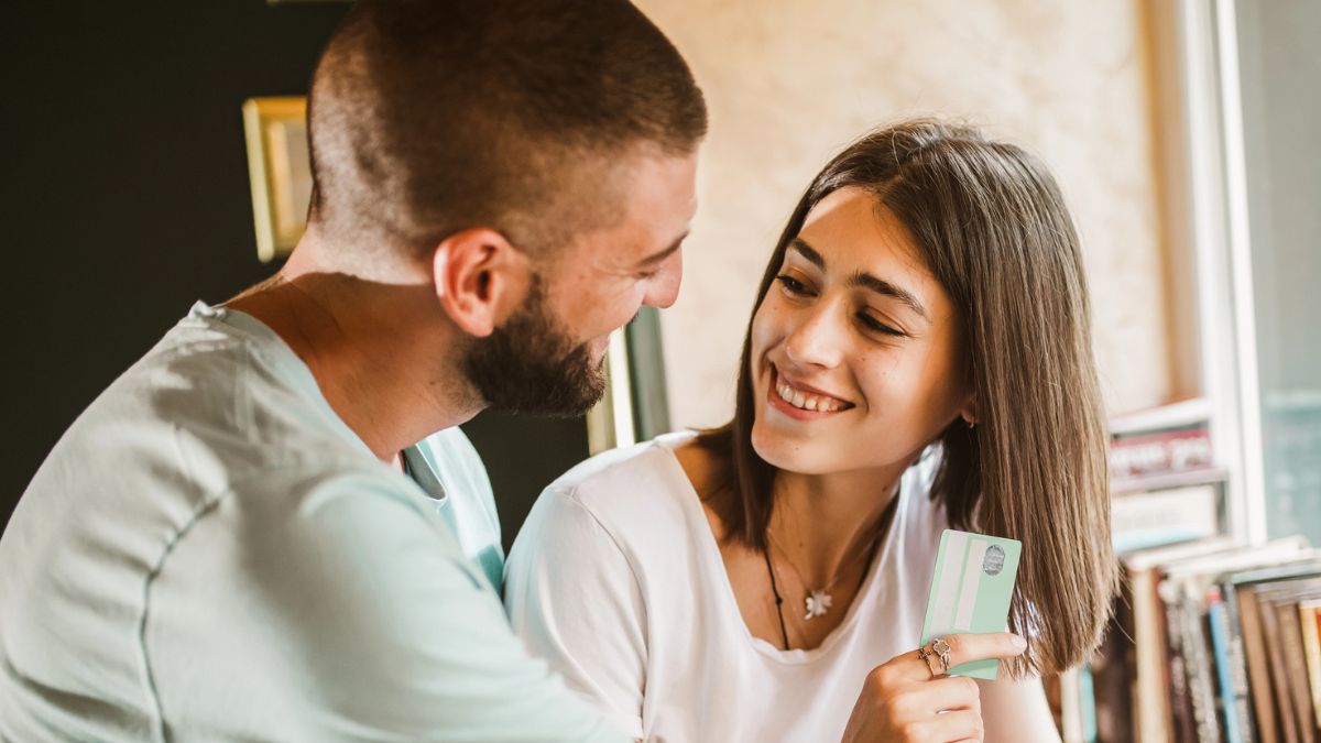 couple smiling at one another with credit card
