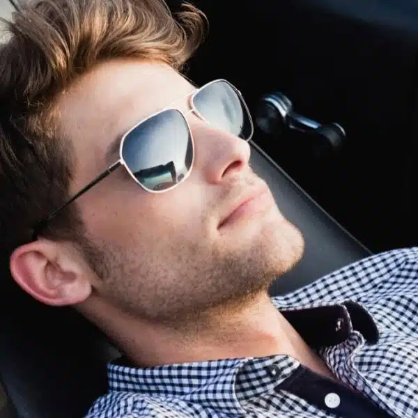 man laying back in car with sunglasses