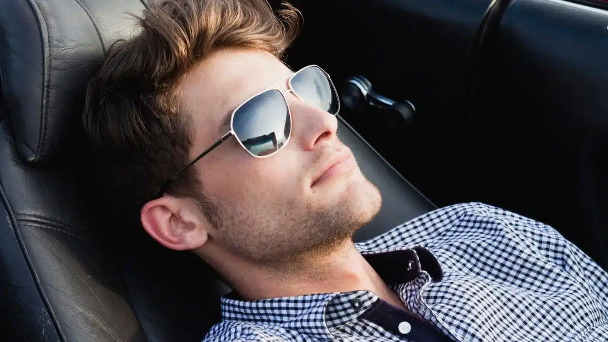 man laying back in car with sunglasses
