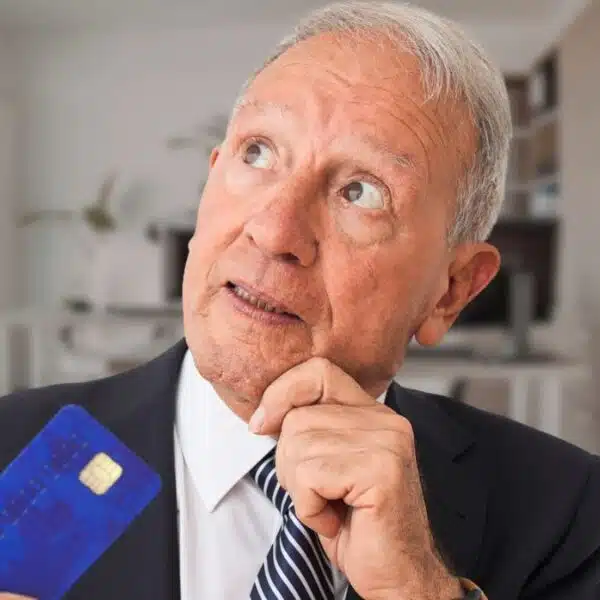 mature man in an office holding a credit card