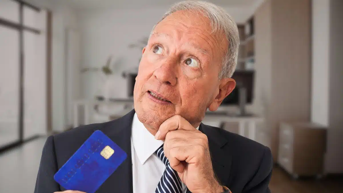 mature man in an office holding a credit card