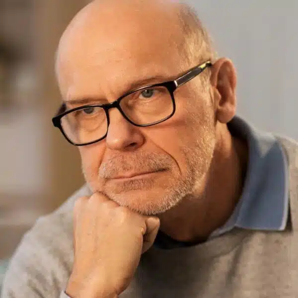 senior man thinking glasses living room