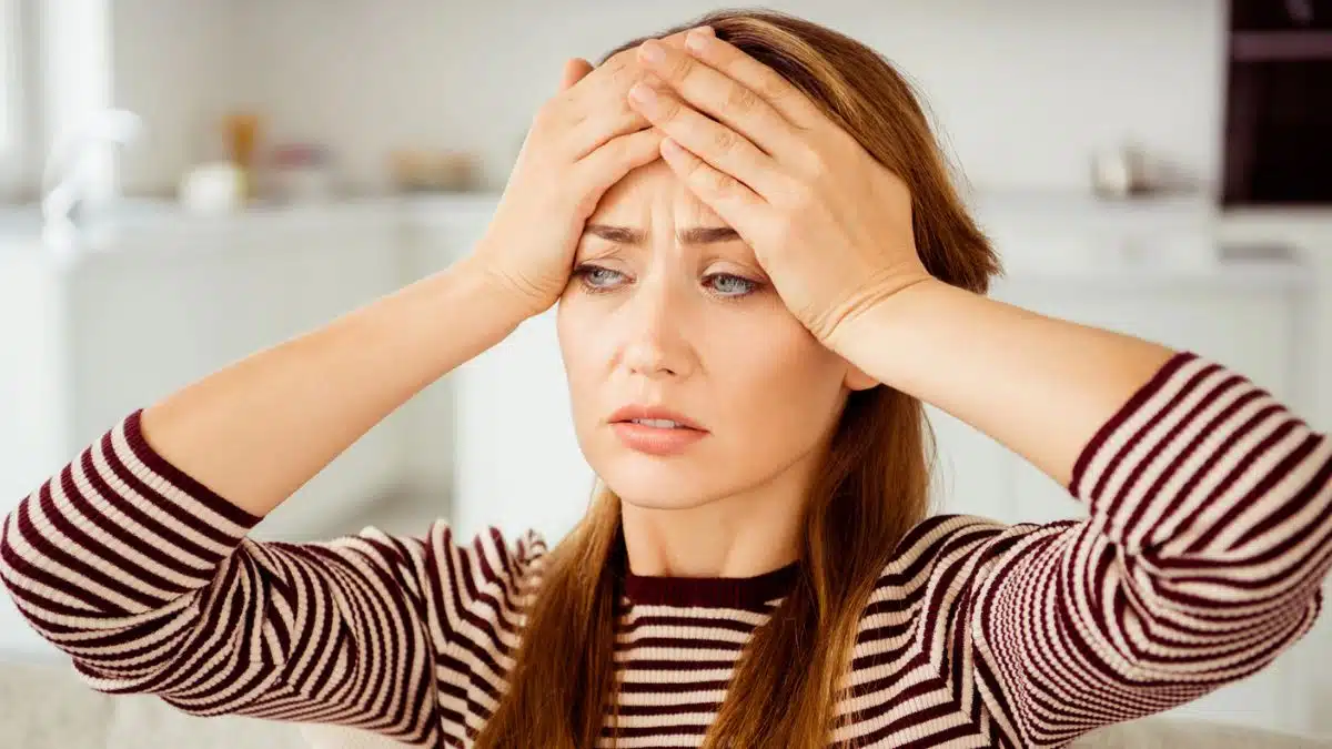woman holding her head striped shirt
