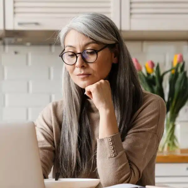 woman thinking laptop kitchen