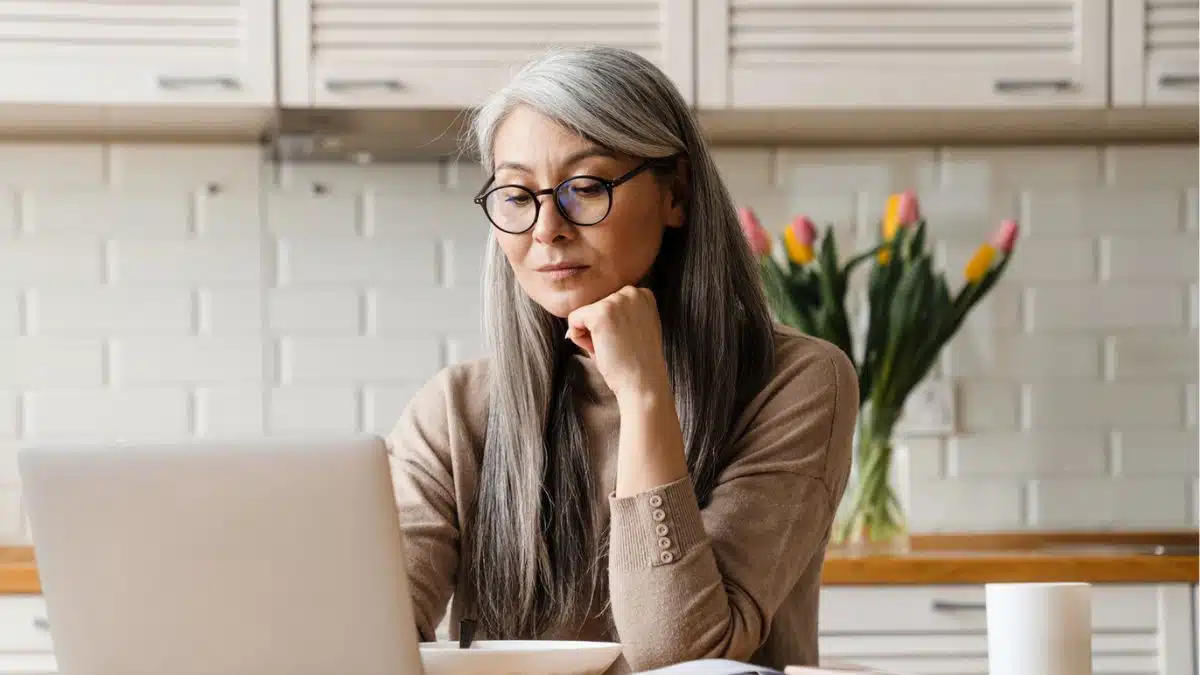 woman thinking laptop kitchen