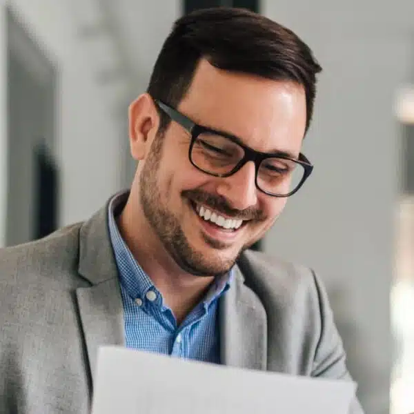 man glasses reviewing documents with laptop