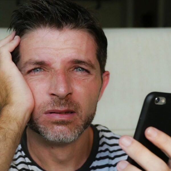 man looking at his phone tired